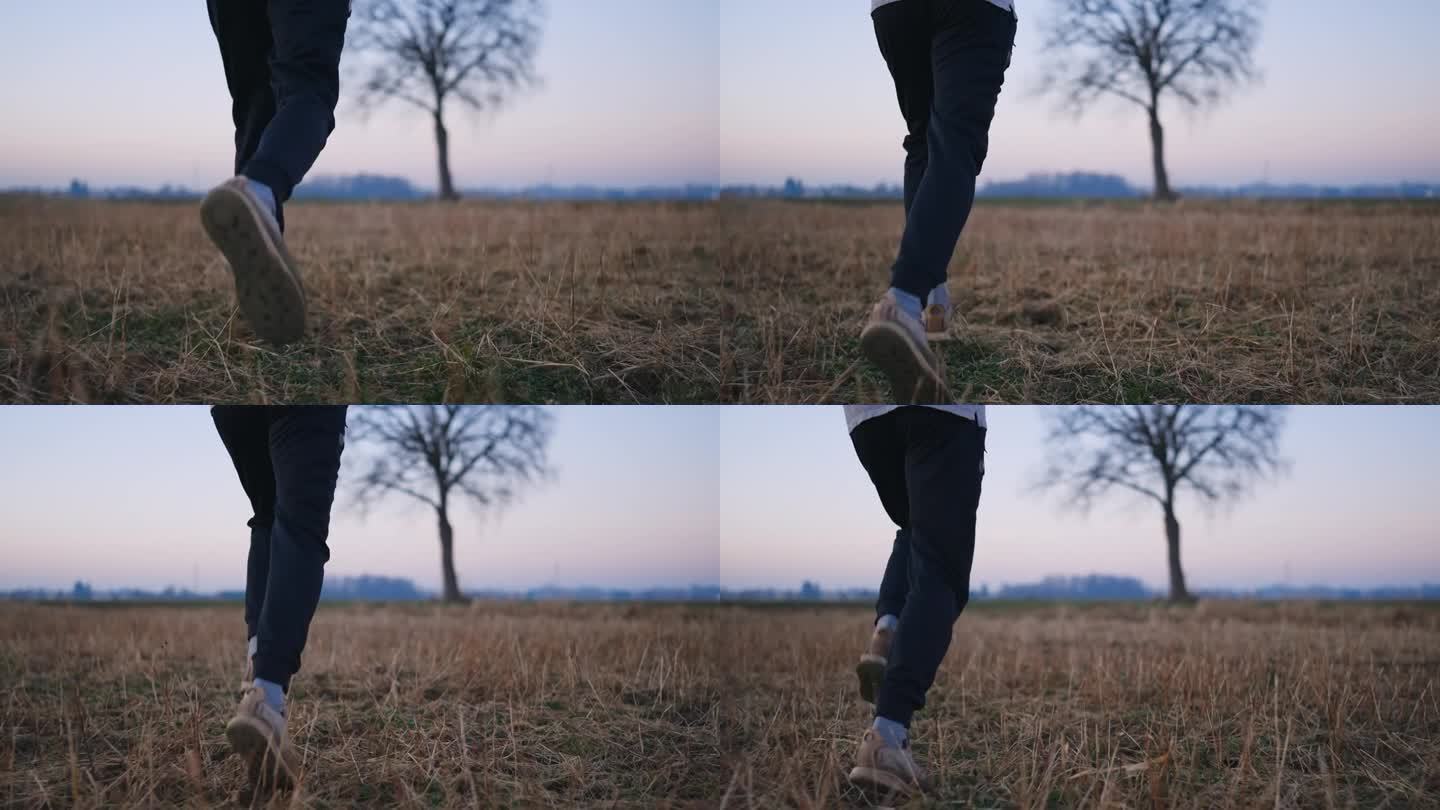 运动青年在乡间干草地上奔跑的背影低剖面跟踪镜头
