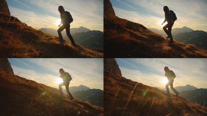 SLO MO独自一人在山峰中:日落时在长满草的山坡上徒步上山的女人