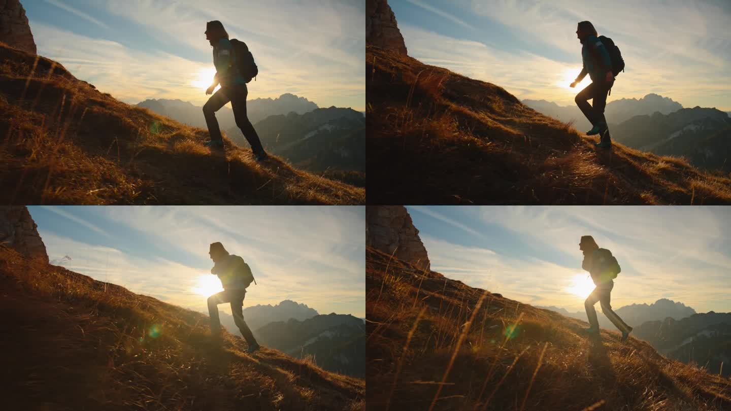 SLO MO独自一人在山峰中:日落时在长满草的山坡上徒步上山的女人