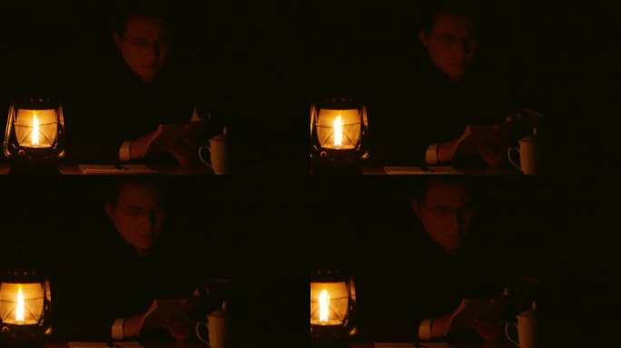 男人在煤油灯前翻书读书