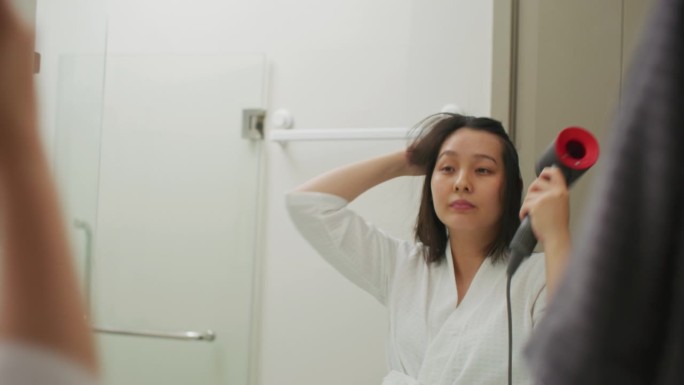 亚洲女人上班前先把头发吹干，穿好衣服。