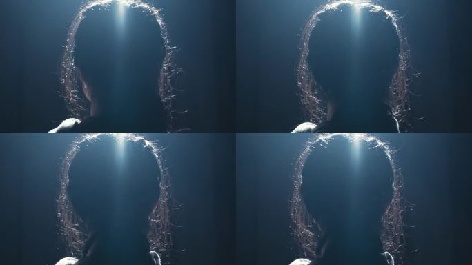一个人的剪影，背部照明在头发周围创造了一个光环效果。