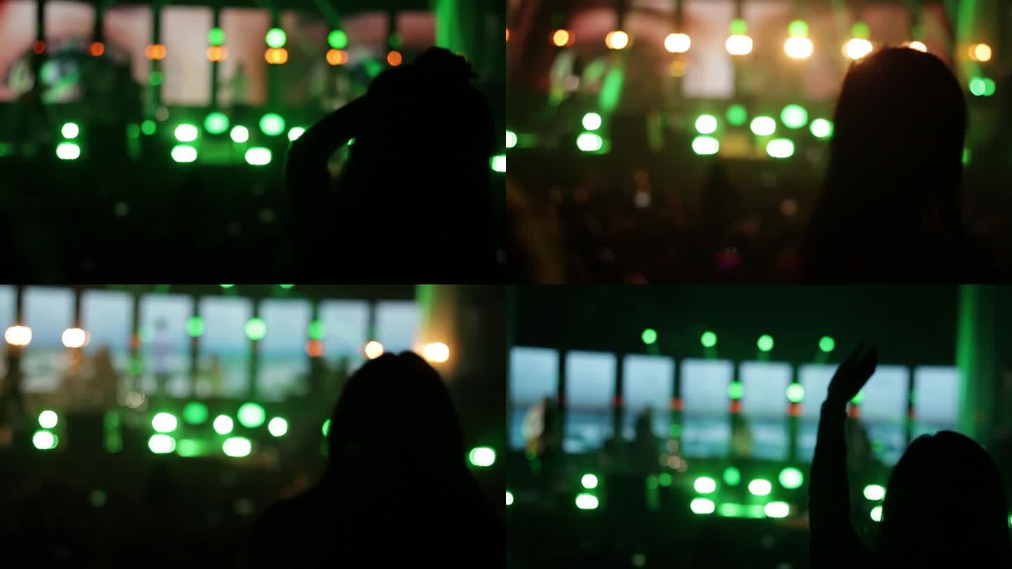 音乐会上的女人剪影。舞台上亮绿灯。充满活力的节日气氛，充满活力的音乐