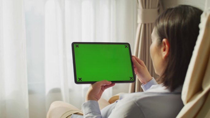 一个女人在用绿屏的平板电脑