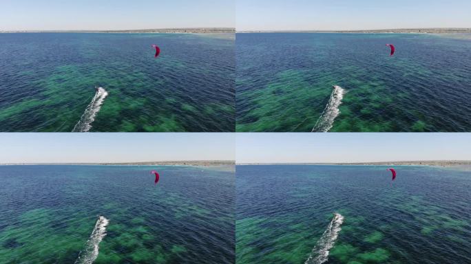 鸟瞰图年轻的白人女运动员骑着风筝在大海上冲浪。水上运动