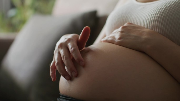 孕妇双手抚摸腹部的微距特写
