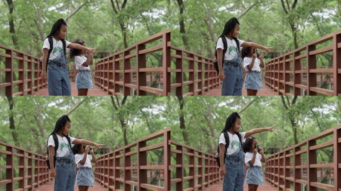 在红树林学习中心，姐姐和妹妹在木桥上手拉手学习生态系统。