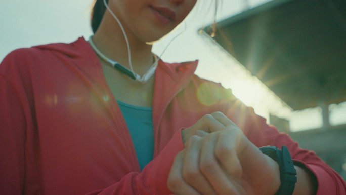年轻的亚洲女运动员跑步者在户外跑步前检查智能手表的进度和看智能手表心率监测器的特写。健康的锻炼。