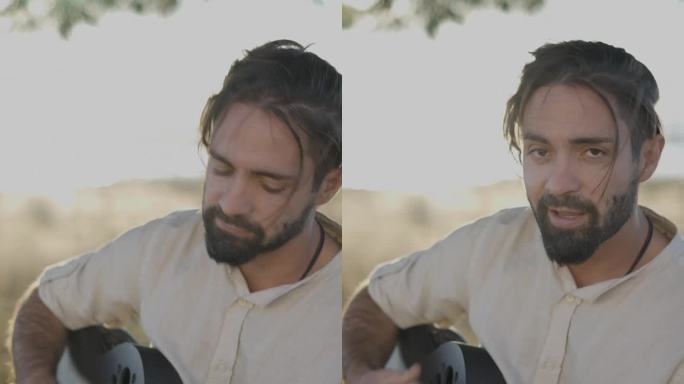 英俊的男吉他手在西班牙乡村的夕阳下，弹着经典的原声吉他，唱着歌，看着镜头