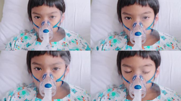 生病的亚洲男孩带着吸入器面罩呼吸，看着镜头近距离的正面视图
