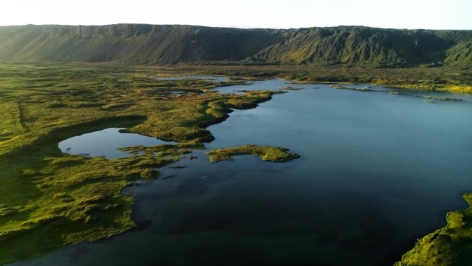 冰岛乡村一片宽阔的田野中间，雨水形成了一个湖泊，景色优美。