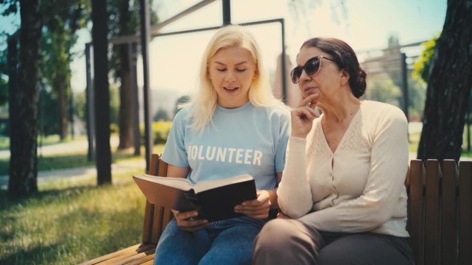 一位女性志愿者正在为一位视力受损的老年妇女读书