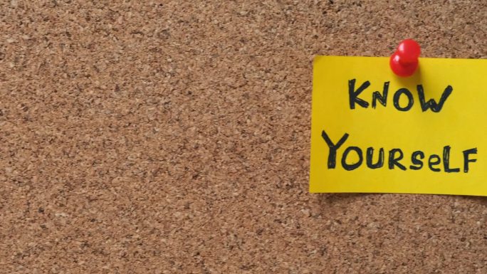 一张黄色的纸条，上面写着“认识你自己”，别在一块软木板上。