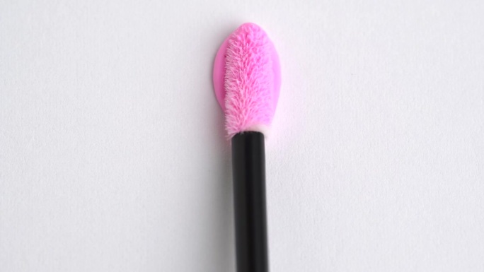 亮粉色唇彩垂直笔画。粉色口红，唇彩质地心形。化妆品在时髦的粉红色涂抹涂抹样品样品。