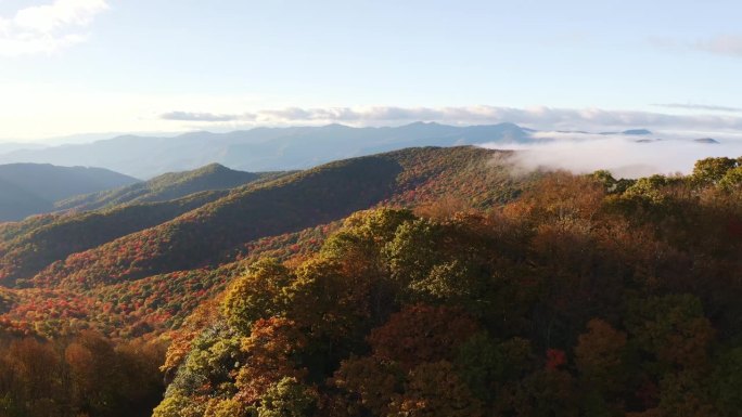 鸟瞰蓝岭公园大道之间的彩色秋天山与山峰覆盖在雾和云在日落