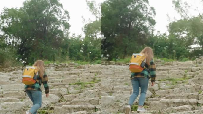 垂直视频。一名女游客背着双肩包爬上古希腊圆形剧场的台阶，这里已经被森林覆盖了数千年。
