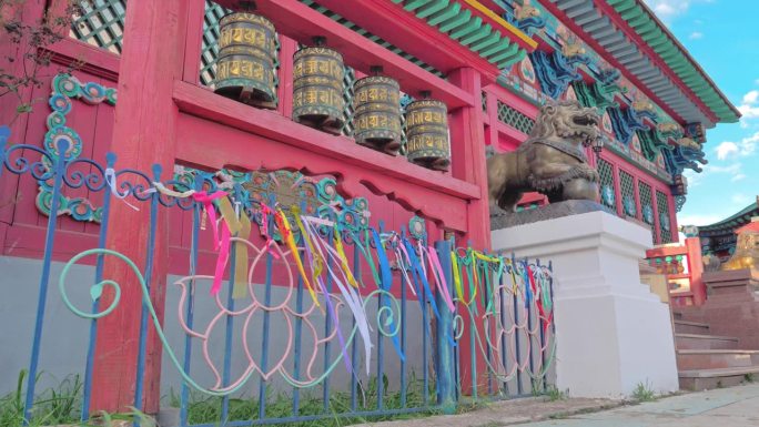 俄罗斯，伊沃尔金斯克，2021年9月7日:一座木制寺庙前古老的佛教经轮的自下而上的照片。彩带在风中摇