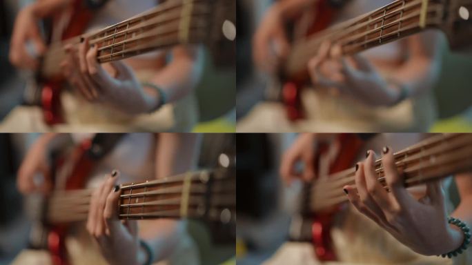 特写镜头。一个不知名的女孩用手指在低音吉他的琴颈上拨动琴弦。
