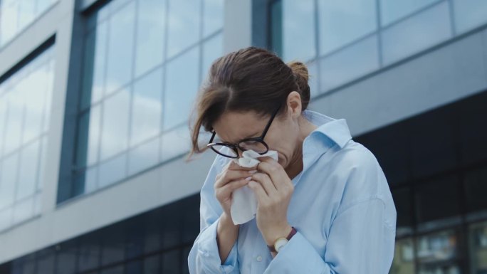 不健康的女人打喷嚏用纸巾擤鼻子，季节性过敏