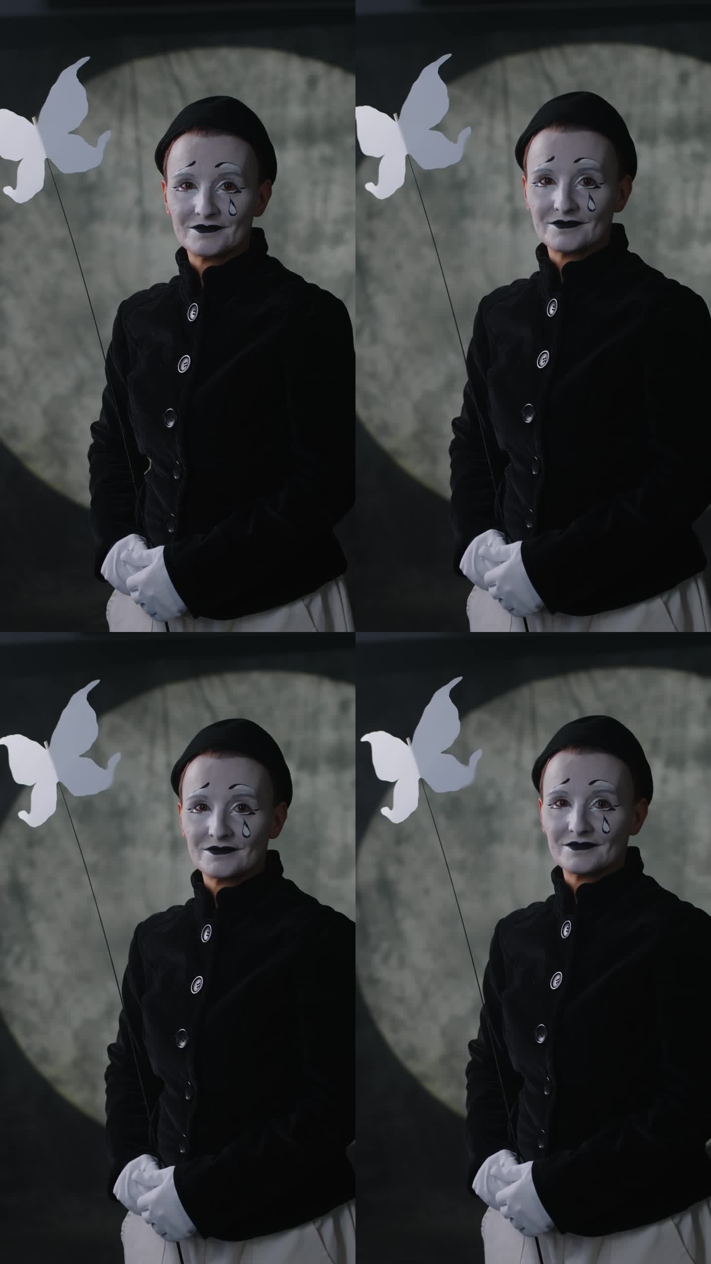 女哑剧艺术家在黑暗舞台上的纸蝴蝶肖像