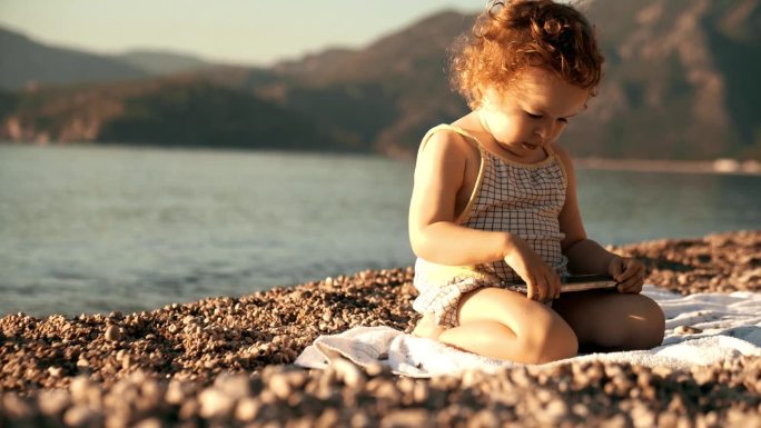 不开心的小女孩在海滩上玩智能手机。旅游应用和新的用户概念