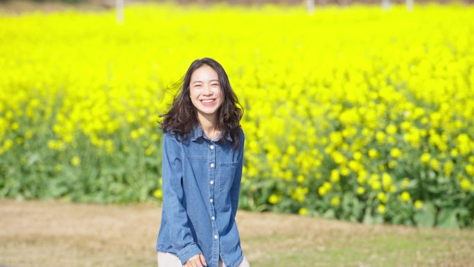 青春美女漫步阳光油菜花海春天田野