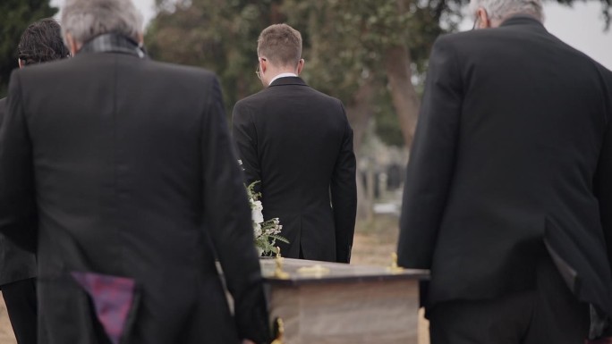 男子、棺材和护柩者一起走在室外的葬礼仪式上。死亡，悲伤和集体抬棺材在墓地，墓地和家庭服务的人哀悼在大