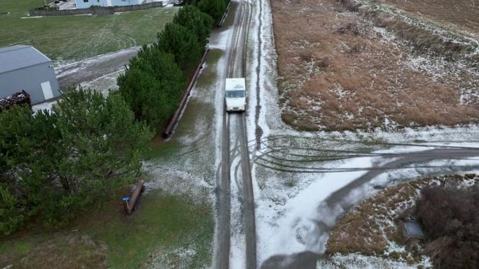 无人机拍摄的USPS车辆行驶在积雪覆盖的农村道路上投递邮件。