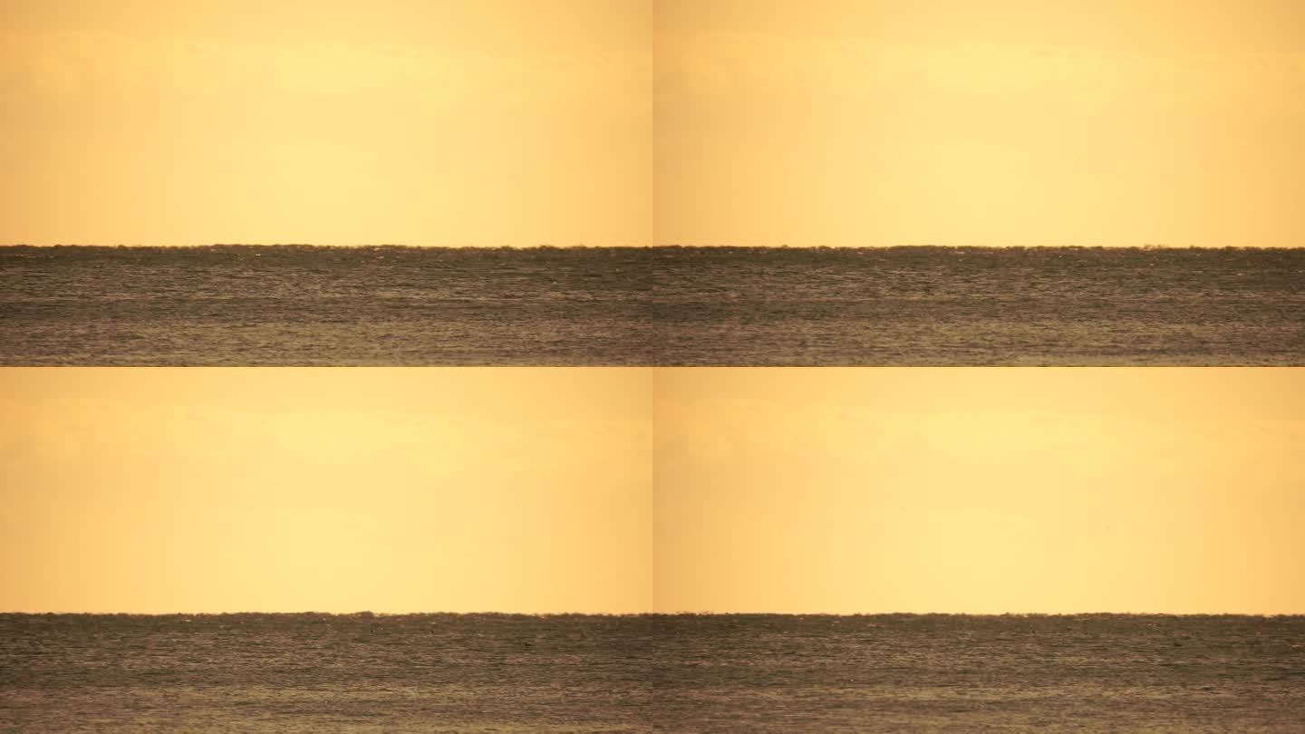 地平线上出现了货船的幻影。船在海上航行。温暖的金色水面上的小波浪和来自太阳的散景灯光。大海、大自然和