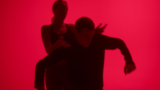 专业的年轻舞蹈编导在工作室的红色霓虹灯背景上跳现代舞。才华横溢的舞者在舞蹈音乐视频、双人舞、二人转中