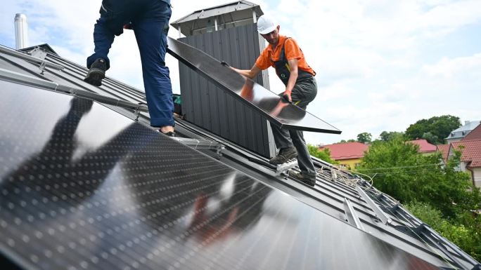 工人们在屋顶上建造太阳能电池板系统。安装人员携带光伏太阳能组件