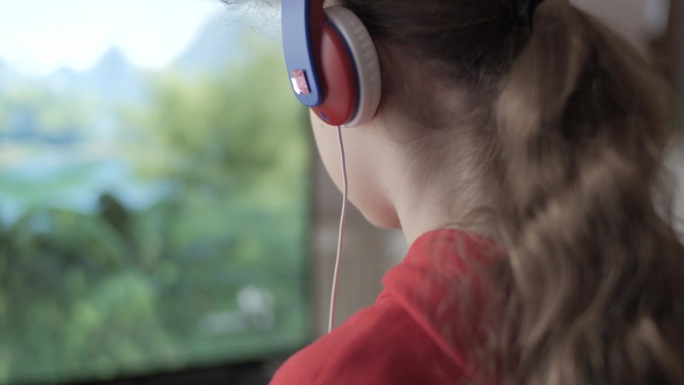 戴耳机的女孩在主机上玩电脑多人视频游戏。儿童玩家在电视屏幕上玩电子游戏。戴着耳机和操纵杆的人在大电视