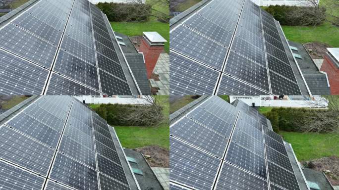 美国社区屋顶上安装的太阳能板上空缓慢飞行。郊区车库屋顶光伏。空中鸟眼。