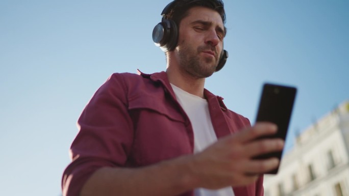戴着耳机的快乐男性通过音乐应用程序发现新的艺术家和流派。