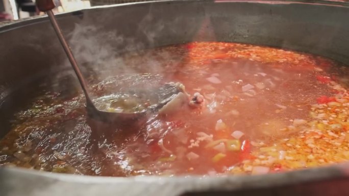 厨师用漏勺在大锅里拌肉汤和蔬菜