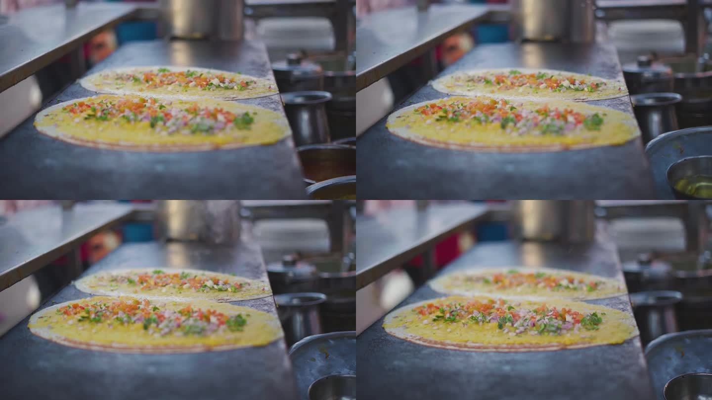 在印度的一个街头小吃摊上，多萨在平底铁锅上用土豆泥和蔬菜烹饪南印度菜的特写镜头