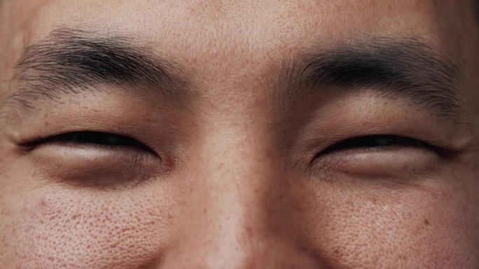 亚洲男人的肖像，快乐的脸和微笑的眼睛看着镜头近距离。具有青年民族特征的朝鲜族人的快乐情感视野。青年学