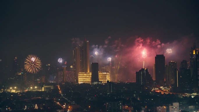 午夜时分，泰国曼谷市中心的一家百货商店和一座灯火通明的建筑上，燃放着新年烟花