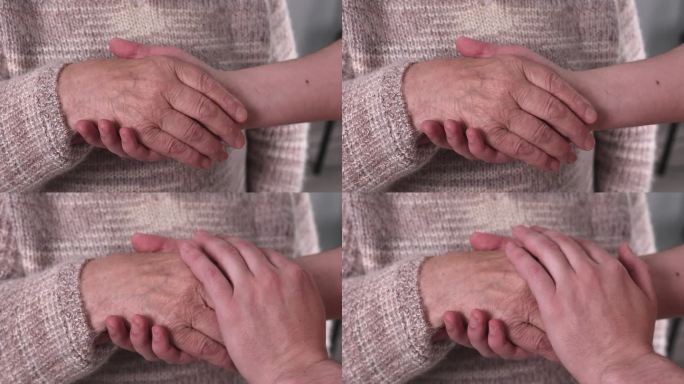特写:老妇人的手牵着孩子的手。