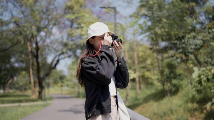 一位女摄影师在度假时用她的相机在城市公园拍照。