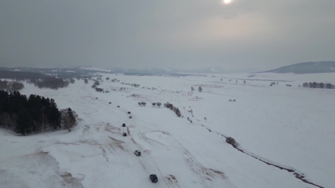 冬季航拍越野车队穿过白雪覆盖的草原