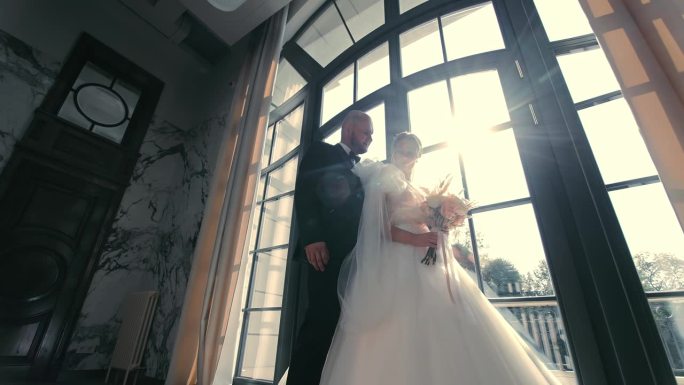 婚礼上的优雅夫妇，新婚夫妇站在一扇大窗户旁，阳光照进来。