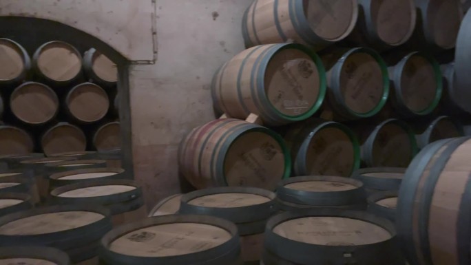陈年的酒桶堆放在昏暗的地窖里。酒庄储藏的陈年橡木