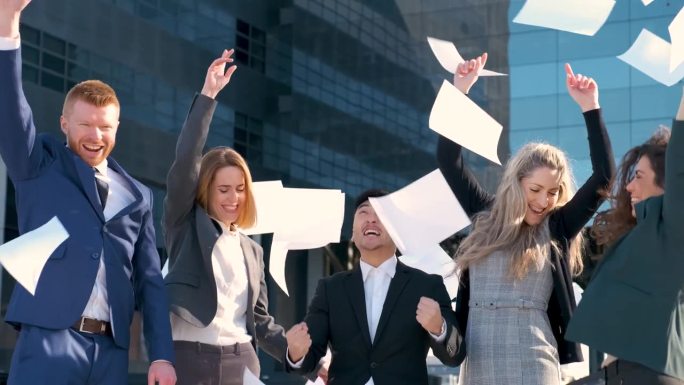 欢快的商业团队向空中抛掷文件庆祝成功。
