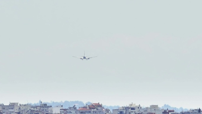 大型飞机接近令人惊叹的塞萨洛尼基机场，从远处俯瞰建筑物。一架大型商用飞机飞过塞萨洛尼基附近的一个令人
