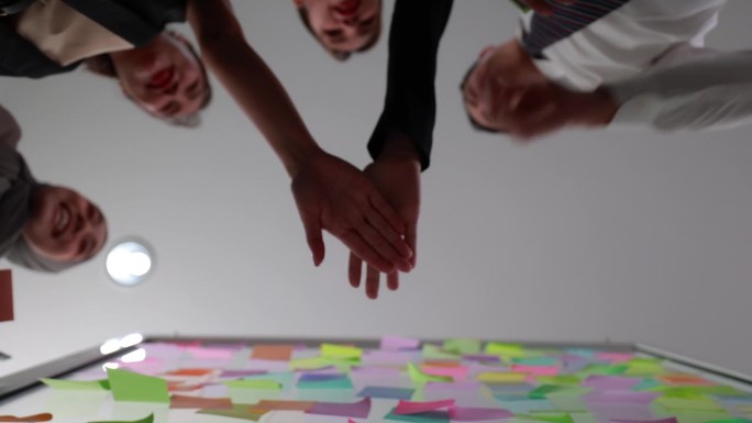 办公室里的团队合作:商务人员团结一致，双手堆叠成一个象征成就的手势