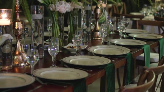 优雅的婚宴桌设计，配有玻璃器皿、盘子和天然花卉。