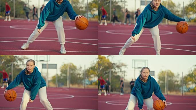 夏天，一个金发女孩穿着蓝色卫衣和白色裤子，在街头球场的红色地板上弹起一个橙色的篮球