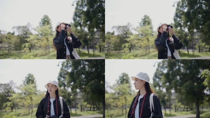 休闲风格的年轻亚洲女性在度假时站在自然公园用她的相机拍照。