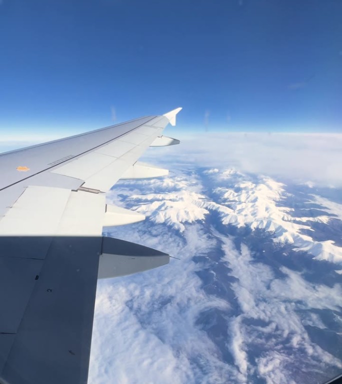 从飞机上看飞机的机翼和云，向窗外看美丽的山景，蓝天的景色，从飞机舷窗看天空和云